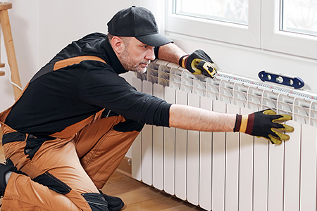 Mann arbeitet an einer Heizung